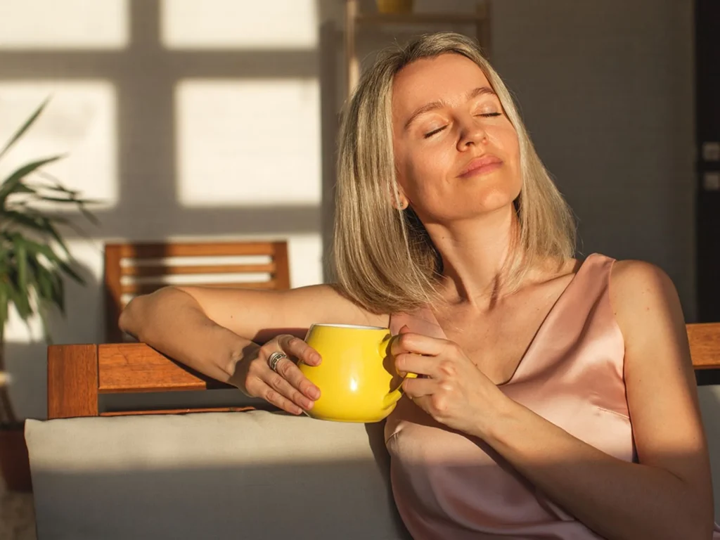 A close-up of a woman enjoying tea, walking outdoors, or taking a breath