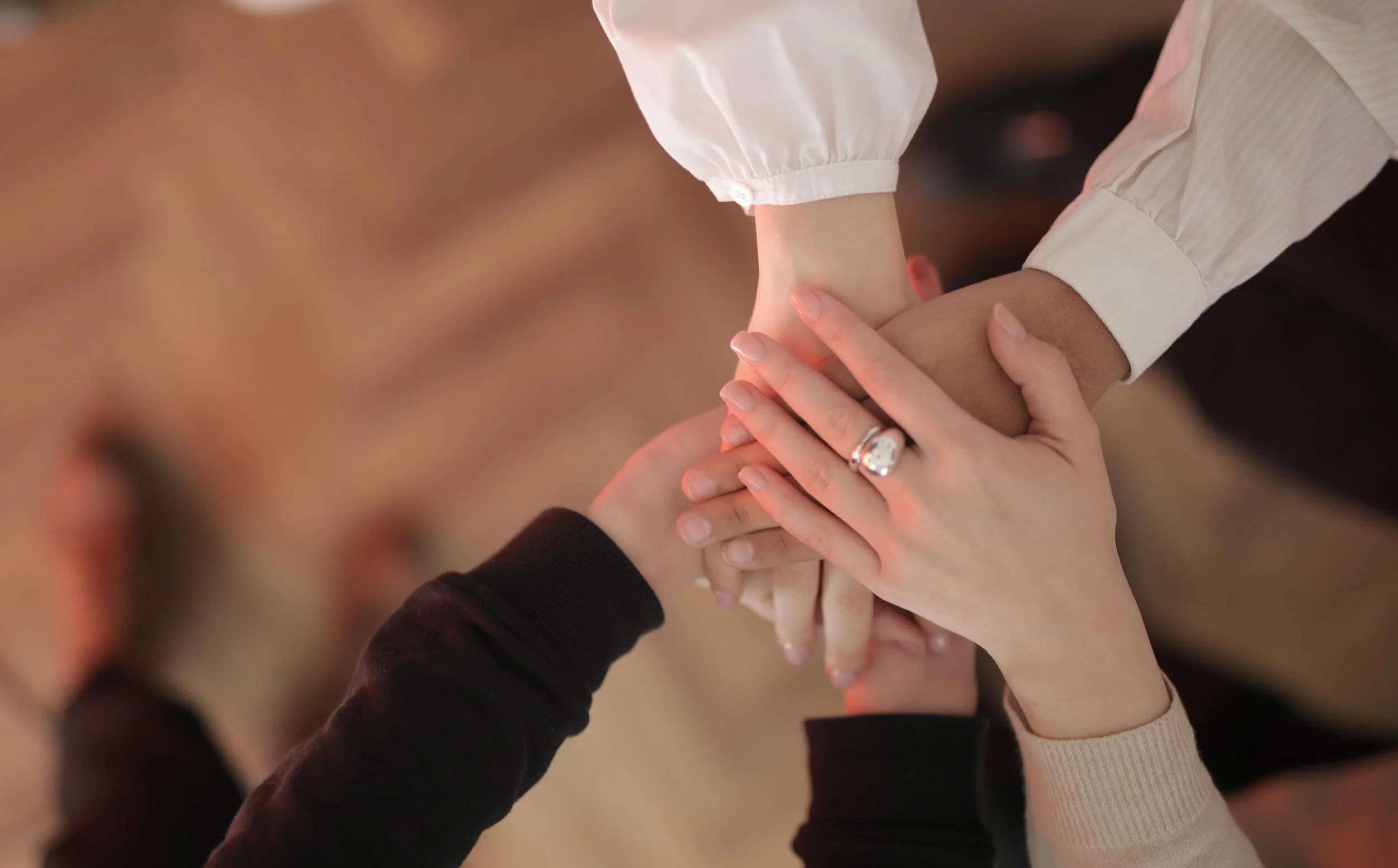 Hands stacked together symbolizing teamwork, unity, and support.
